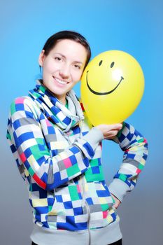 girl with a yellow smiley balloon against blue