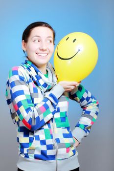 girl with a yellow smiley balloon against blue