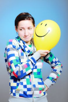girl with a yellow smiley balloon against blue