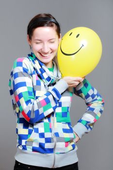 girl with a yellow smiley balloon against grey background