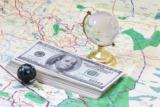 A few dollars lying on the map, with glass globe and compass