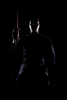 portrait of a kendo fighter with bokken, against black backgroung