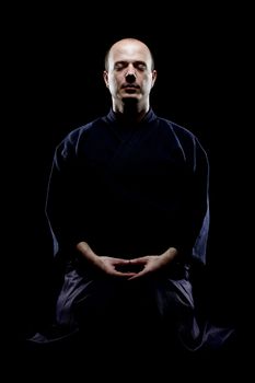 portrait of a kendo fighter meditating, against black backgroung