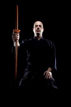 portrait of a kendo fighter with bokken, against black backgroung