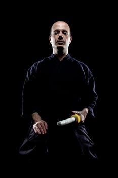 portrait of a kendo fighter with shinai, against black backgroung