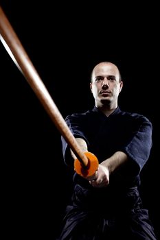 portrait of a kendo fighter with bokken, against black backgroung