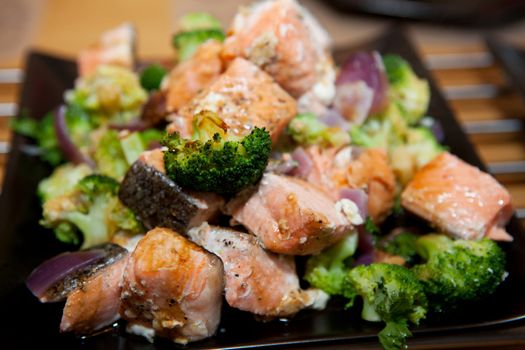 Delicious meal with salmon, broccoli and onions in closeup