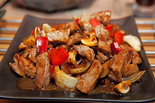 Delicious meal with meat, red paprika and onions in closeup