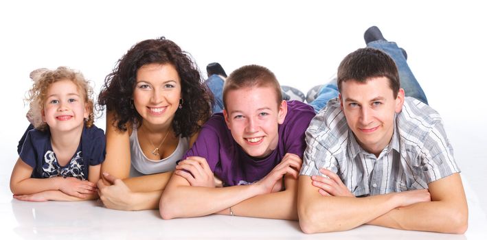 Beautiful middle aged couple lying with cute kids and smiling over white background