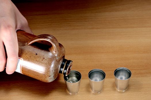 pouring alcohol into a small metal cups