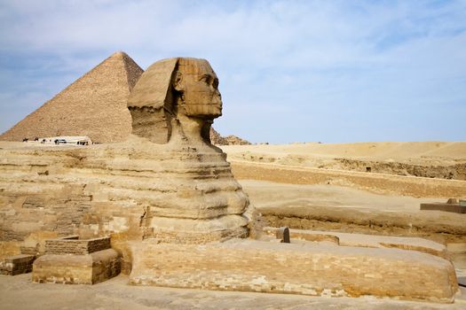 Ancient Egyptian Sphinx with old historic pyramid in Giza
