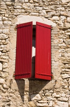 stone wall with window and red typical french shutters