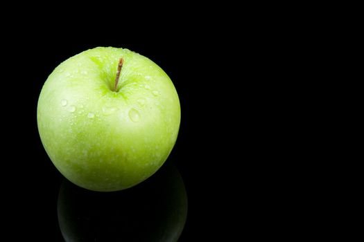 fresh juicy green apple with waterdrops over black background