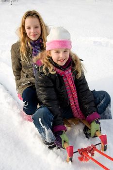 Two girls on a sled in the snow