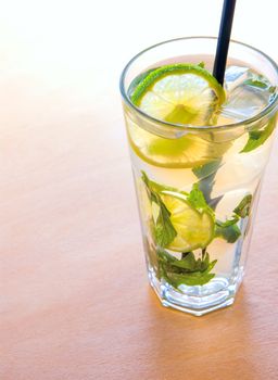 mojito cocktails with lime, mint leaves and ice on wooden placemat background