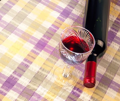 bottle of wine and a glass against a background of bright cloth