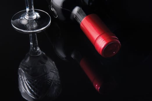 bottle of wine and a glass of red label on a black mirrored background