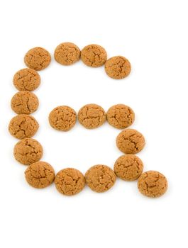 Ginger nuts, pepernoten, in the shape of letter G isolated on white background. Typical Dutch candy for Sinterklaas event in december.