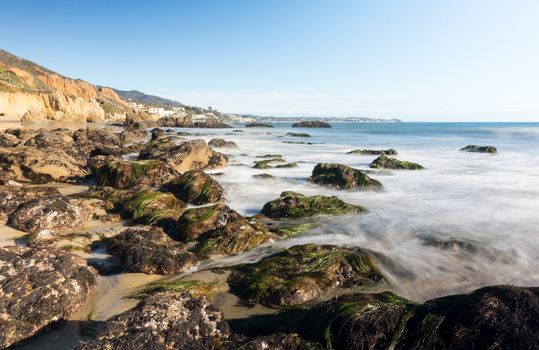 Seaweed covered rocks by ocean on El Matador State Beach Malibu California