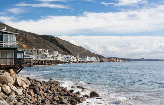 Modern houses overhang ocean and waves in Malibu California