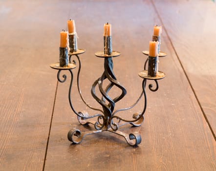 Old iron candlestick holder and candles lit by light from window on old wooden table