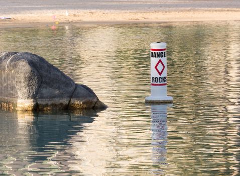 Humorous sign for Danger Rocks in small seaside pool with single rock
