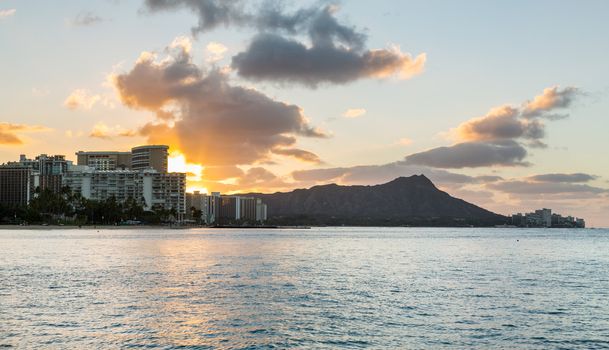 Early morning sunrise at dawn illuminates clouds over Diamond Head and Waikiki Beach area of Oahu in Hawaii