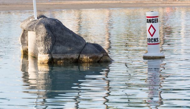 Humorous sign for Danger Rocks in small seaside pool with single rock