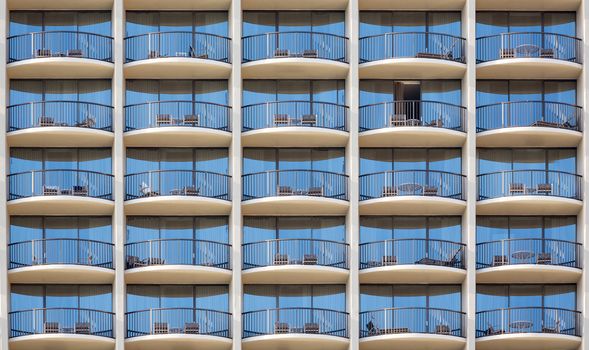 Pattern of hotel room balconies in modern building with one patio door open