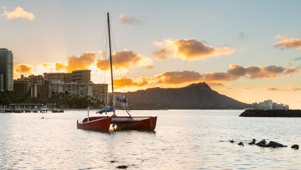 Early morning sunrise at dawn illuminates clouds over Diamond Head and Waikiki Beach area of Oahu in Hawaii