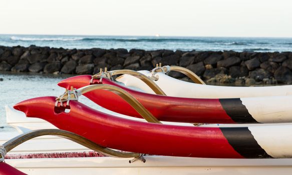 Early morning sunrise at dawn illuminates outrigger of traditional Hawaiian canoe in Waikiki Beach area of Oahu in Hawaii