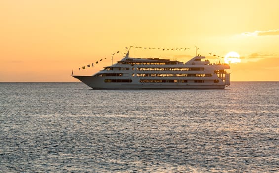 Cruise ship or ferry boat sailing towards setting sun off coast of Waikiki Oahu Hawaii