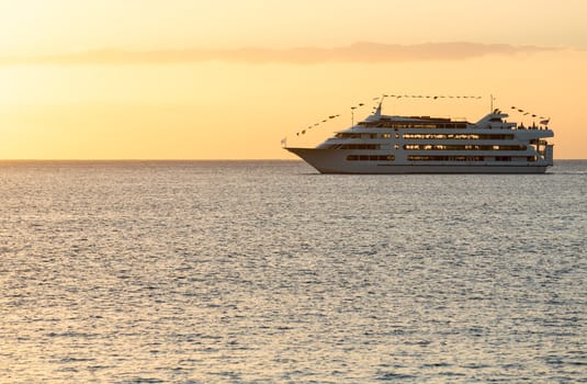 Cruise ship or ferry boat sailing towards setting sun off coast of Waikiki Oahu Hawaii
