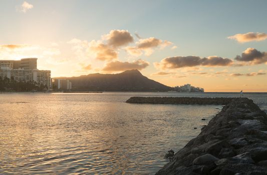 Early morning sunrise at dawn illuminates clouds over Diamond Head and Waikiki Beach area of Oahu in Hawaii