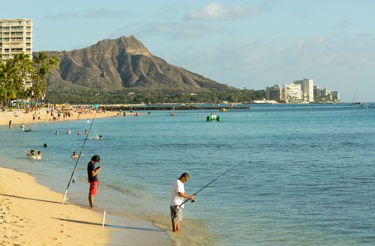 WAIKIKI, HI - JANUARY 20: Fishermen fishing off busy Hawaii beach on 20 January 2012. The Waikiki Beach restoration project was completed early 2012.