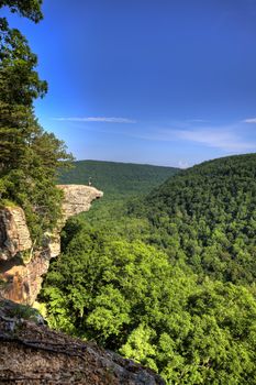 This famous place on the Whitaker's Point trail is the number 1 most photographed spot in Arkansas. A male hiker enjoys the view standing hundreds of feet above the Ozark mountains forest below.