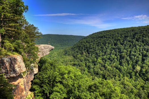 This famous place on the Whitaker's Point trail is the number 1 most photographed spot in Arkansas. A male hiker enjoys the view standing hundreds of feet above the Ozark mountains forest below.