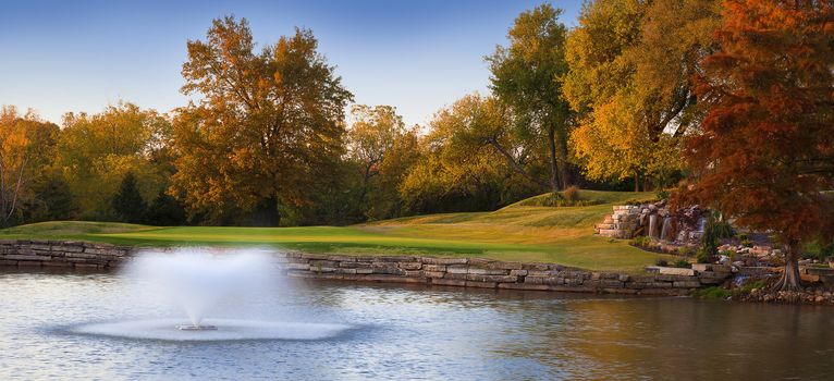 A beautiful colorful Autumn landscape with a flowing fountain in the water.