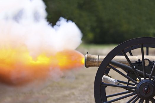 A close up shot of a Civil War cannon fireing at a civil war re-enactment.