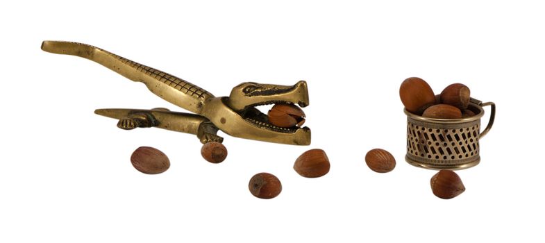 steel crocodile nut hull shell crush tool and small cup full of ripe cobnuts isolated on white