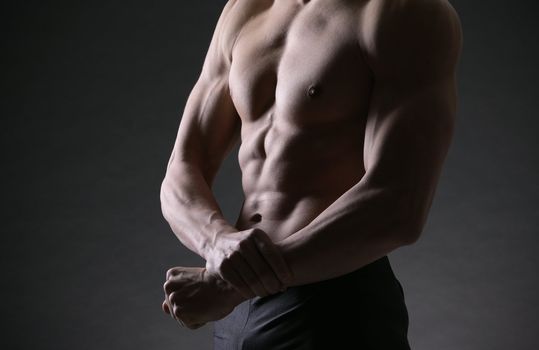 A shirtless male of a healthy fit young guy flexing his biceps