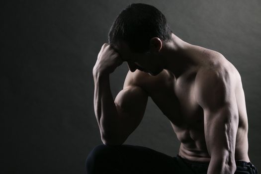 Bodybuilder concentrating on dark background