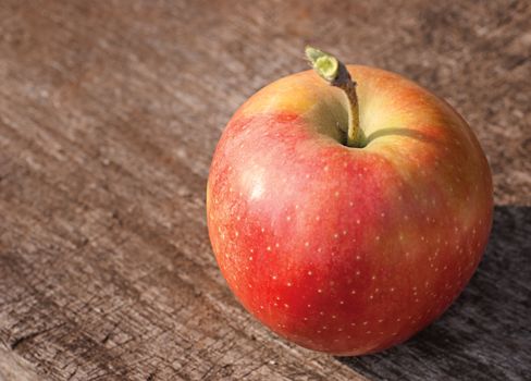 Red apple on old wooden table from above, with copy space.