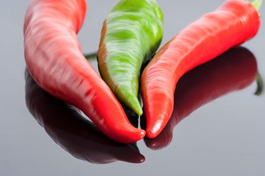 red and green hot chili peppers  background with reflection