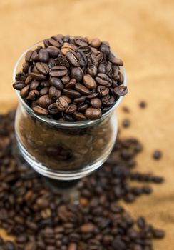 Grains of black roasted coffee in transparent cup