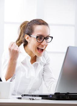 Young businesswoman cheering, screaming at laptop