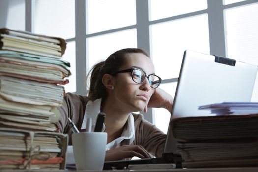 Businesswoman frustated with work, has a lot of paperwork at the office