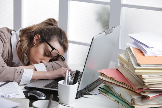 Tired businesswoman sleeping on the desk, in front of the computer screen.
