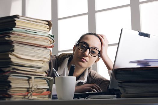 Young tired businesswoman with tons of documents