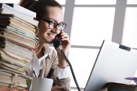 Beautiful young woman working in office and making a phone call
